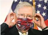  ?? JACQUELYN MARTIN/AP ?? Senate Majority Leader Mitch McConnell replaces his face mask Tuesday after speaking at a news conference on Capitol Hill.