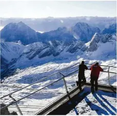  ??  ?? Zwei Mitarbeite­r blicken auf das geschlosse­ne Skigebiet auf der Zugspitze. Wegen der Corona-pandemie ist Skifahren nicht möglich.