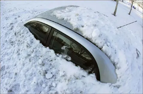  ?? Nam Y. Huh/Associated Press ?? A car is covered by snow in Chicago. At least five fatalities are being blamed on a storm that stretched from Texas to Maine.