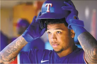  ?? Smiley N. Pool / TNS / Dallas Morning News 2020 ?? Texas outfielder Willie Calhoun puts on his batting helmet in the dugout before a spring training game against the Rockies in Scottsdale, Ariz., on Feb. 26, 2020.