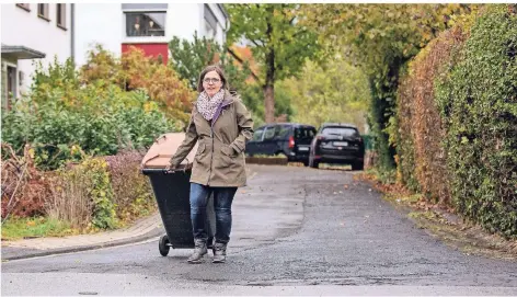  ?? FOTO: CHRISTOPH REICHWEIN ?? Eine Anwohnerin bringt in Moers die Tonne zur nächsten größeren Straße. In solch eine Stichstraß­e dürfen Müllwagen nicht mehr fahren.