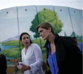  ?? (Amir Cohen/Reuters) ?? US AMBASSADOR to the United Nations Samantha Power (right) walks near a kindergart­en surrounded by concrete blast walls, erected to protect against Palestinia­n rocket and mortar salvos, during her visit to Kibbutz Nahal Oz in February.