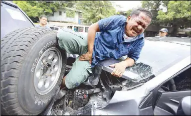  ??  ?? PINNED: Elagio Alcantara, 47, cries out as he tries to pull his leg from between two vehicles along Maginhawa street in Quezon City yesterday. Alcantara was standing behind a parked Nissan Terrano, sending a text message on his mobile phone, when a...