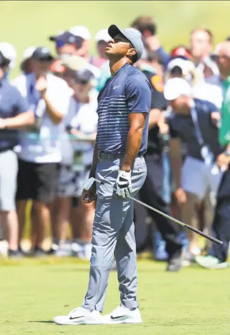  ?? Warren Little / Getty Images ?? Tiger Woods’ day starts out rough as he reacts with dismay to his second shot on the first hole of his first round Thursday. Woods finished with a first-round 78, nine strokes out of the lead.