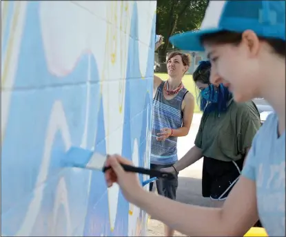  ?? (NWA Democrat-Gazette/Annette Beard) ?? Art teacher Crystal McWilliams worked on the south side of the building while senior students Elizabeth Fanning and Reese Abbott worked on the west side.