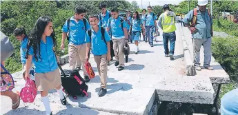  ??  ?? PASO. Un grupo de niños camina por el puente provisiona­l sobre el río Humuya de Santa Rita, Yoro.