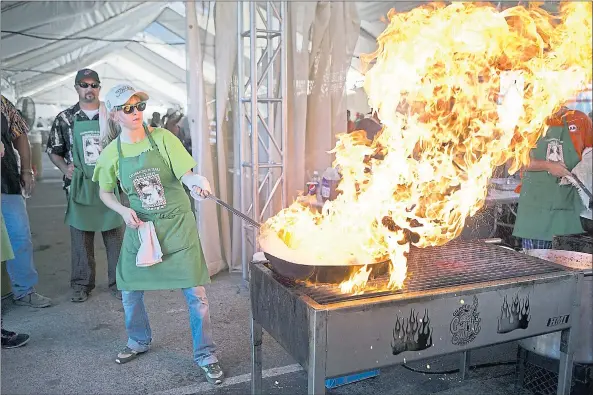  ?? STAFF FILE PHOTO ?? Pyro Chef Ashley Janisch cooks calamari at the 2014 Gilroy Garlic Festival. The renowned event returns to Gilroy’s Christmas Hill Park July 27-29.