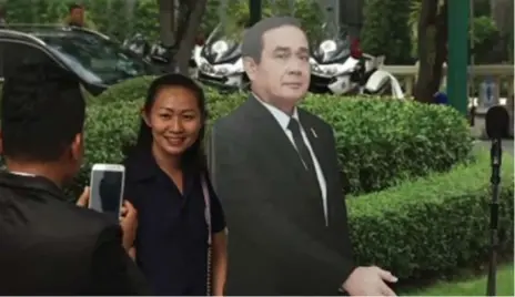  ?? THE ASSOCIATED PRESS ?? A woman poses with a cardboard cut-out of Thai Prime Minister Prayuth Chan-ocha that he placed next to a microphone during a press conference.