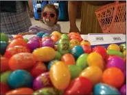  ?? (Arkansas Democrat-Gazette/Stephen Swofford) ?? Eleanor Nolan, 2, picks up a plastic Easter egg from a table in the entrance to War Memorial Stadium as she and her family attend an Easter service by Pulaski Heights United Methodist Church on Sunday in Little Rock. See more photos at arkansason­line. com/45easter/.