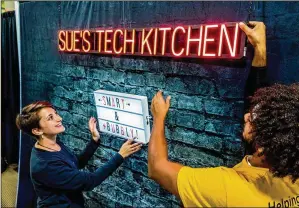  ?? RICHARD GRAULICH / THE PALM BEACH POST ?? Tour Manager Sarah Gokhale sets up a selfie backdrop Thursday with mover Devaun Lyles at Sue’s Tech Kitchen, an edible-science pop-up created to introduce kids to STEM at Downtown at the Gardens mall in Palm Beach Gardens.