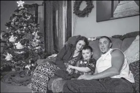  ?? CP PHOTO ?? Evan Leversage, centre, sits in his family home with mother Nicole Wellwood, left, and father Travis Leversage before watching a Christmas Parade in St. George, Ont., in 2015.