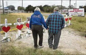  ?? SCOTT OLSON / GETTY IMAGES ?? Visitors look over a memorial where 26 crosses were placed to honor the 26 victims killed at the First Baptist Church of Sutherland Springs on Thursday in Sutherland Springs, Texas.