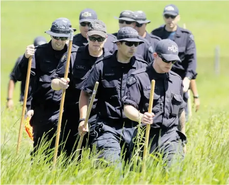  ?? COLLEEN DE NEVE/POSTMEDIA NEWS ?? Police comb a field near a slough north of Airdrie on Monday in search of clues to the disappeara­nce of Nathan O’Brien, 5; Alvin Liknes and Kathryn Liknes, all of Calgary.