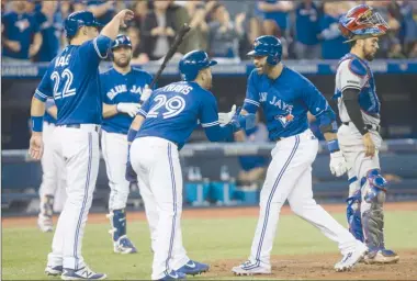  ?? The Canadian Press ?? Toronto Blue Jays right fielder Jose Bautista, centre right, celebrates with teammates Devon Travis (29) and Luke Maile (22) after hitting a three-run homer as Texas Rangers catcher Robinson Chirinos, right, looks on during fifth-inning AL action in...
