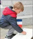  ??  ?? Un enfant des écoles dépose une bougie