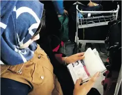  ?? ASSAD MUHSIN / THE ASSOCIATED PRESS ?? Mariam Ali looks at her U. S. visa as she and her husband prepare to board a flight on their way to the States.