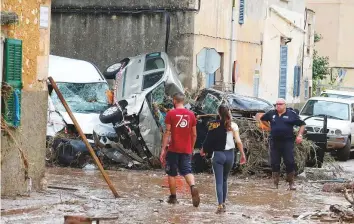  ?? Reuters ?? Locals walk among the debris-ridden streets as heavy rain and flash floods hit Sant Llorenc de Cardassar on the island of Majorca, Spain, yesterday.