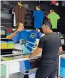  ?? MAYELA LÓPEZ ?? María García muestra una camiseta a Gustavo Guevara en una tienda en San José.