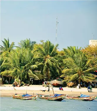  ?? ?? Carnival of colour: Fishing boats by a beach in The Gambia. Inset right, a fruit-seller