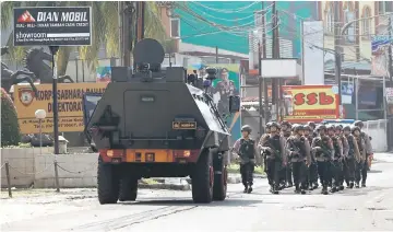  ??  ?? A group of mobile brigade policemen patrol near an armoured car at the Mobile Police Brigade (Brimob) headquarte­rs in Depok. — Reuters photo