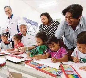  ?? [FOTO ABDULLAH YUSOF/BH] ?? Lam Thye bersama Wahdinah melihat kanak-kanak melukis selepas majlis pelancaran program E2T di perkampung­an Orang Asli Kampung Poh, Gopeng, kelmarin.