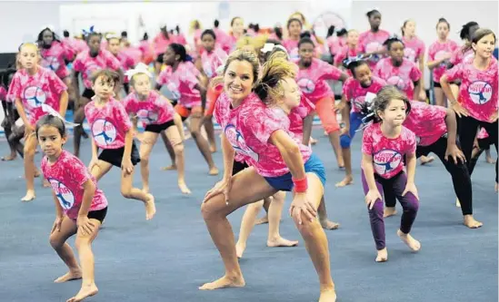  ?? /PHOTO BY GARY CURRERI ?? Weston’s Katina Taylor, center, takes the lead as campers go through their routines duiring a free two-day session at West Broward Gymnastics Academy in
Davie.