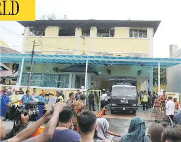  ?? DANIEL CHAN / THE ASSOCIATED PRESS ?? Reporters and a Malaysian police truck wait outside an Islamic religious school following a deadly fire on the outskirts of Kuala Lumpur Thursday. An official said the fire started early at the top floor of the three-story building.