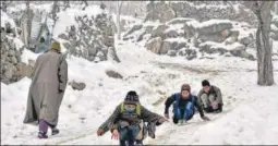  ?? PTI ?? Children play on a snow-covered road on the outskirts of Srinagar on Wednesday. As per Met officials, Kashmir’s Gulmarg recorded a low of minus 10 degree Celsius. Officials have forecast a fresh spell of snow and rain across Jammu and Kashmir beginning from Friday.