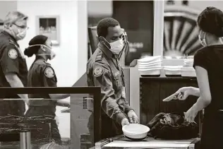  ?? Elaine Thompson / Associated Press ?? TSA officers wear protective masks at a security screening area at Seattle-tacoma Internatio­nal Airport. Airlines say they’re stepping up security on flights to Washington.