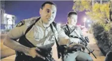  ??  ?? Police officers advise people to take cover near the scene of a shooting in Las Vegas on Sunday night.