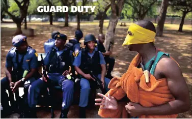  ?? PICTURE: OUPA MOKOENA ?? A student with a slingshot around his neck walks past a group of police officers during the #FeesMustFa­ll protest near the Union Buildings in Pretoria yesterday.