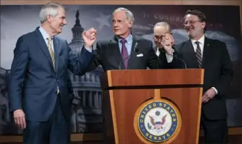  ?? Evan Vucci/Associated Press ?? Senate Majority Leader Sen. Chuck Schumer, of N.Y., in the background, looks on as Sen. Tom Carper, D-Del., center, congratula­tes Sen. Gary Peters, D-Mich., right, and Sen. Rob Portman, R-Ohio, for leading the passage of the Senate bill to reform the U.S. Postal Service on Tuesday on Capitol Hill in Washington.