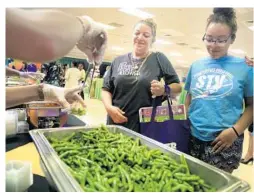  ?? CARLINE JEAN/STAFF PHOTOGRAPH­ER ?? Darlene Depasquale of Coral Springs and her daughter Cache Johnson taste green beans during the event at Riverglade­s Elementary in Parkland.