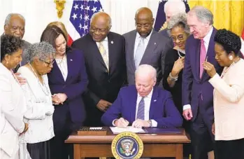  ?? EVAN VUCCI AP ?? President Joe Biden signs the Juneteenth National Independen­ce Day Act on Thursday, surrounded by lawmakers, Vice President Kamala Harris and Opal Lee (second from left), who campaigned for the holiday.