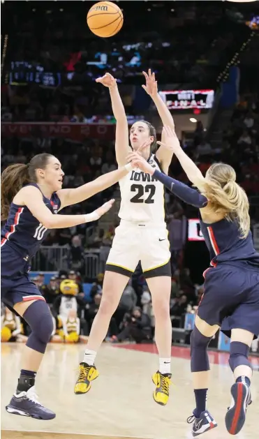  ?? GETTY IMAGES ?? Iowa star Caitlin Clark shoots over UConn’s Nika Muhl (left) and Paige Bueckers in the first half Friday in Cleveland.