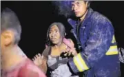  ?? REUTERS ?? A rescue worker helps a woman covered with ash.