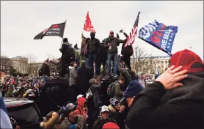  ?? Jon Cherry / Getty Images ?? A group of pro-Trump protesters wave flags while standing on an armored police vehicle on the grounds of the Capitol Building on Wednesday in Washington, D.C. A pro-Trump mob stormed the Capitol, breaking windows and clashing with police.