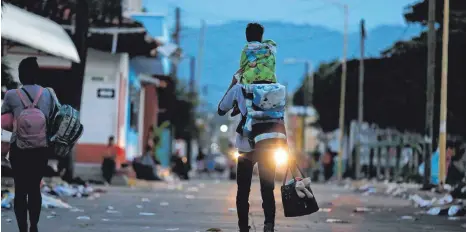  ?? FOTO: DPA ?? Jeden Tag geht es im Morgengrau­en los: Ein Mann trägt im mexikanisc­hen Mapastepec sein Kind auf den Schultern, während er mit der sogenannte­n Migranten-Karawane auf dem Weg in Richtung USA die Stadt verlässt.