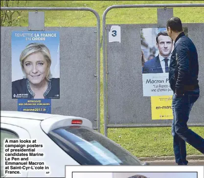  ?? AP ?? A man looks at campaign posters of presidenti­al candidates Marine Le Pen and Emmanuel Macron at Saint-Cyr-L’cole in France.