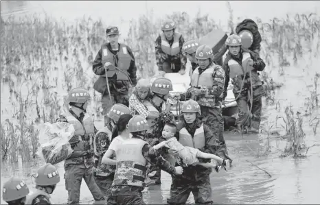  ?? WANG ZICHUANG / FOR CHINA DAILY ?? Armed police rescue villagers besieged by floods in Quanzhou county of Guilin, Guangxi Zhuang autonomous region, on Sunday.