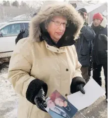  ??  ?? A woman, holding a picture of her husband who died in last week’s fire, arrives for a memorial service for victims on Sunday.