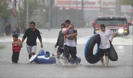  ?? JOE RAEDLE/ GETTY IMAGES ?? Houston residents make their way down a flooded street after leaving their homes on Sunday. With the city facing catastroph­ic damage from tropical storm Harvey, the mayor defended his decision not to issue an evacuation order before the storm hit.
