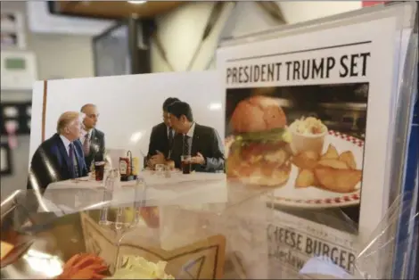  ?? EUGENE HOSHIKO — THE ASSOCIATED PRESS ?? President Donald Trump, left, and Japanese Prime Minister Shinzo Abe, right, are shown at a lunch of hamburgers from Munch’s Burger Shack at Kasumigase­ki Country Club, is displayed at the burger restaurant in Tokyo Thursday, Nov. 16. The cheeseburg­er...