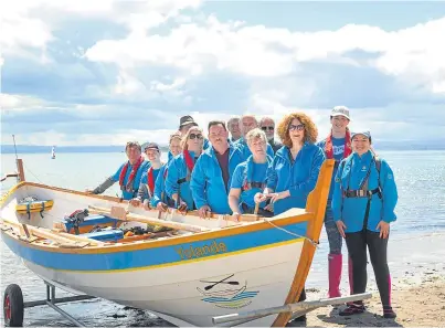  ?? Picture: Sarah Burns. ?? Members of Kinghorn Coastal Rowing Club standing next to their boat ‘Yolande’ on the one-year anniversar­y of their first boat launch.