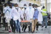  ?? AFP ?? Paramedics use a stretcher to carry the body of a victim from the site of an explosion in Mogadishu on Saturday. —
