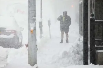  ?? Associated Press ?? A person walks through downtown Buffalo in the snow as a dangerous lake-effect snowstorm paralyzed parts of western and northern New York.