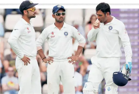  ??  ?? Extraordin­ary times: Mahendra Singh Dhoni (right) reacts after hurting his nger as teammates Ajinkya Rahane and Virat Kohli (left) look on. As a norm a substitute was allowed when a player was injured. A Covid substituti­on is, according to Kumble, “an idea to eliminate the infected person from the remaining part of the game.”afp