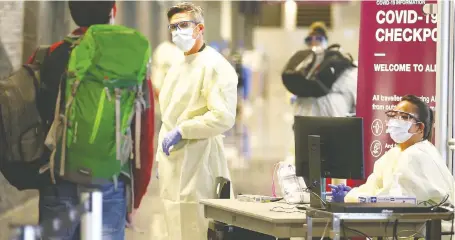  ?? JIM WELLS ?? Passengers entering the internatio­nal arrivals area at the Calgary Internatio­nal Airport are directed by Alberta Health Services staff to a new COVID-19 screening area on Wednesday. The new process, effective immediatel­y, is being introduced at both the Calgary and Edmonton airports.