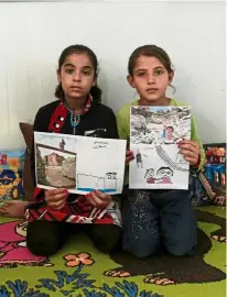  ??  ?? Iraqi refugee children pose with their art therapy drawings and renditions by photograph­er McCarty at Debaga camp for the displaced on the outskirts of Erbil, Iraq.