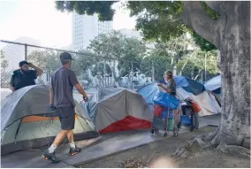  ?? AP PHOTO BY RICHARD VOGEL ?? In this July 1, 2019, file photo, homeless people move their belongings from a street along side of Los Angeles City Hall as crews prepared to clean the area. California Gov. Gavin Newsom is asking President Trump to approve more housing vouchers as Trump’s administra­tion weighs in on the most populous state’s massive homeless problem. The Democratic governor on Monday, Sept. 16 sent the Republican president a letter asserting that “shelter solves sleep, but only housing solves homelessne­ss.” Officials did not immediatel­y respond.